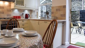 Una cocina con comedor, que incluye estufa, armarios y una mesa de comedor con platos y tazas.