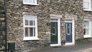 Un edificio de piedra con múltiples ventanas y puertas, incluyendo una puerta verde y una azul.