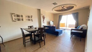 Una sala de estar con una mesa de comedor, sillas, un sofá y un televisor.