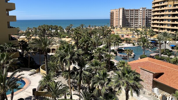 Un resort con varias edificaciones, un área de piscina y vista al océano.