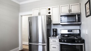 Una cocina con electrodomésticos de acero inoxidable, armarios blancos y un microondas sobre la estufa.