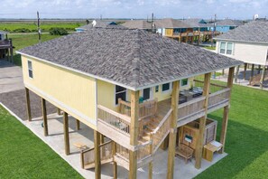Une maison en bois à deux étages, dotée d’un balcon, d’une terrasse et d’un petit espace extérieur aménagé pour s’asseoir.