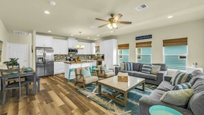 A spacious living area with a sofa, coffee table, and dining table. - Beach Bungalow With Private Hot Tub (Bolivar Peninsula)