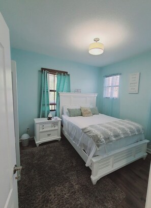A bedroom with a bed, nightstand, and a wall-mounted light fixture.