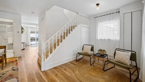 A spacious room with a wooden floor, a white staircase, a round woven rug, and a bed with a green headboard. - Welcome to The Palms! Your summer retreat ~Hot tub (Fort Erie)