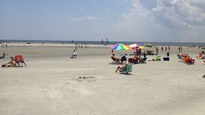 Ein weiter Sandstrand mit bunten Sonnenschirmen und Liegestühlen.