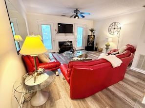 A living room with a red sofa, a glass coffee table, and a television.