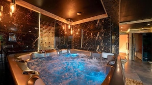 Un área de spa moderna con un jacuzzi, detalles de madera y paredes de mármol.