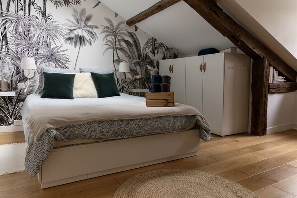 A bedroom with a bed, a wardrobe, a lamp, and a tropical-themed wall mural. - Quiet house in Pau's historic district (Pau)