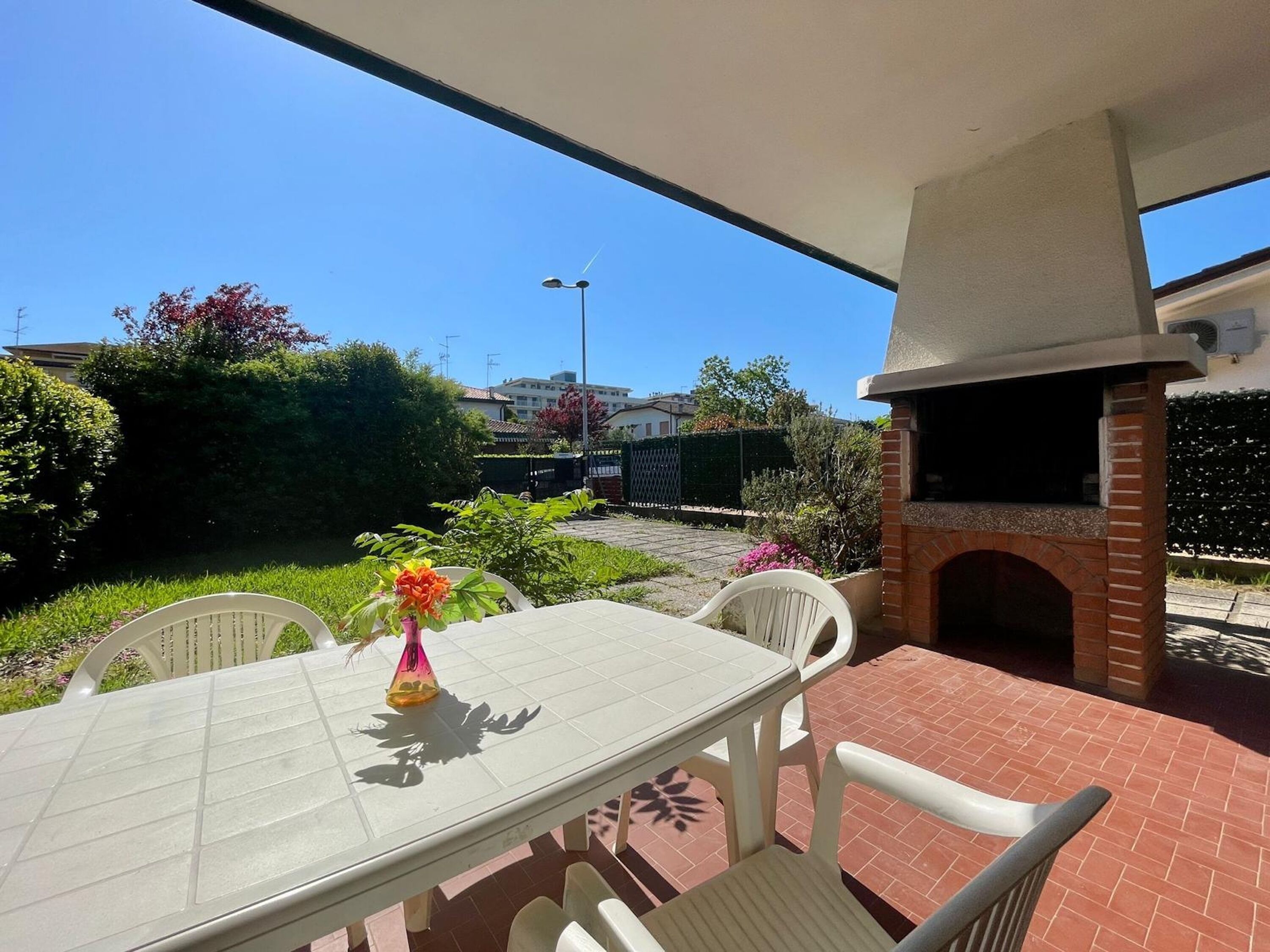 An outdoor patio with a brick oven, a table, and chairs.