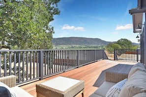 Una terraza con mobiliario exterior y vista a un paisaje montañoso.