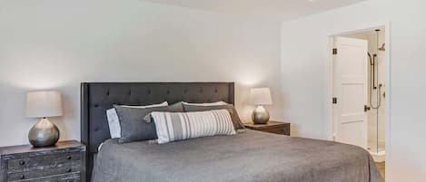 Ein Schlafzimmer mit einem großen Bett, zwei Nachttischen und einer Tür zu einem Badezimmer.