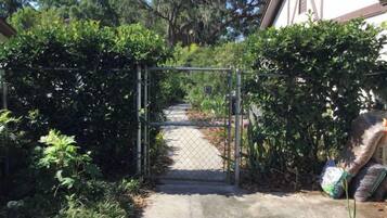 Un camino con puerta de acceso que lleva a un edificio rodeado de exuberante vegetación.