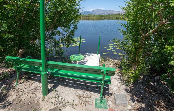 Een groene bank aan een meer, met een helder uitzicht op het water en verre bergen.