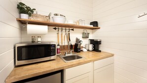 A compact kitchen with a stainless steel microwave, a sink, and a wooden countertop. - The Carson at Ridgeview. Asheville rental! Luxury Glamping! (Alexander)