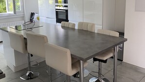 Een moderne keuken met een centraal eiland, witte kastjes en roestvrijstalen apparatuur.