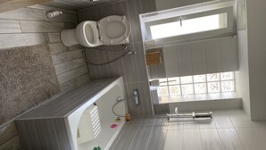 Een moderne badkamer met toilet, douche en wastafel.