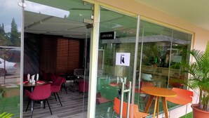 An indoor seating area with red chairs and a wooden table, a glass wall with a 'PUSH' sign, and a 'LION'S DEN' sign.
