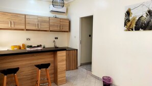 A modern kitchen with wooden cabinets, a black countertop, and two stools.