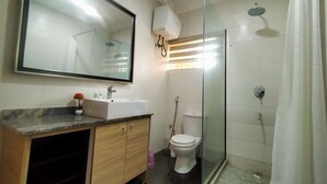 A bathroom with a sink, mirror, toilet, and glass-enclosed shower.