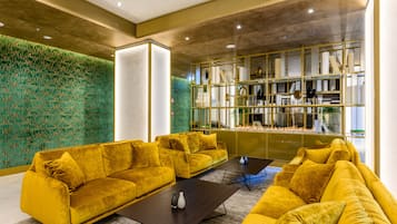 Een moderne lobby met gele banken, een open haard en een groene, structuurrijke muur.