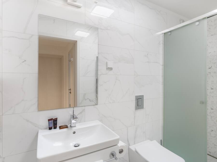 Ein Badezimmer mit Waschbecken, Spiegel und Duschkabine.