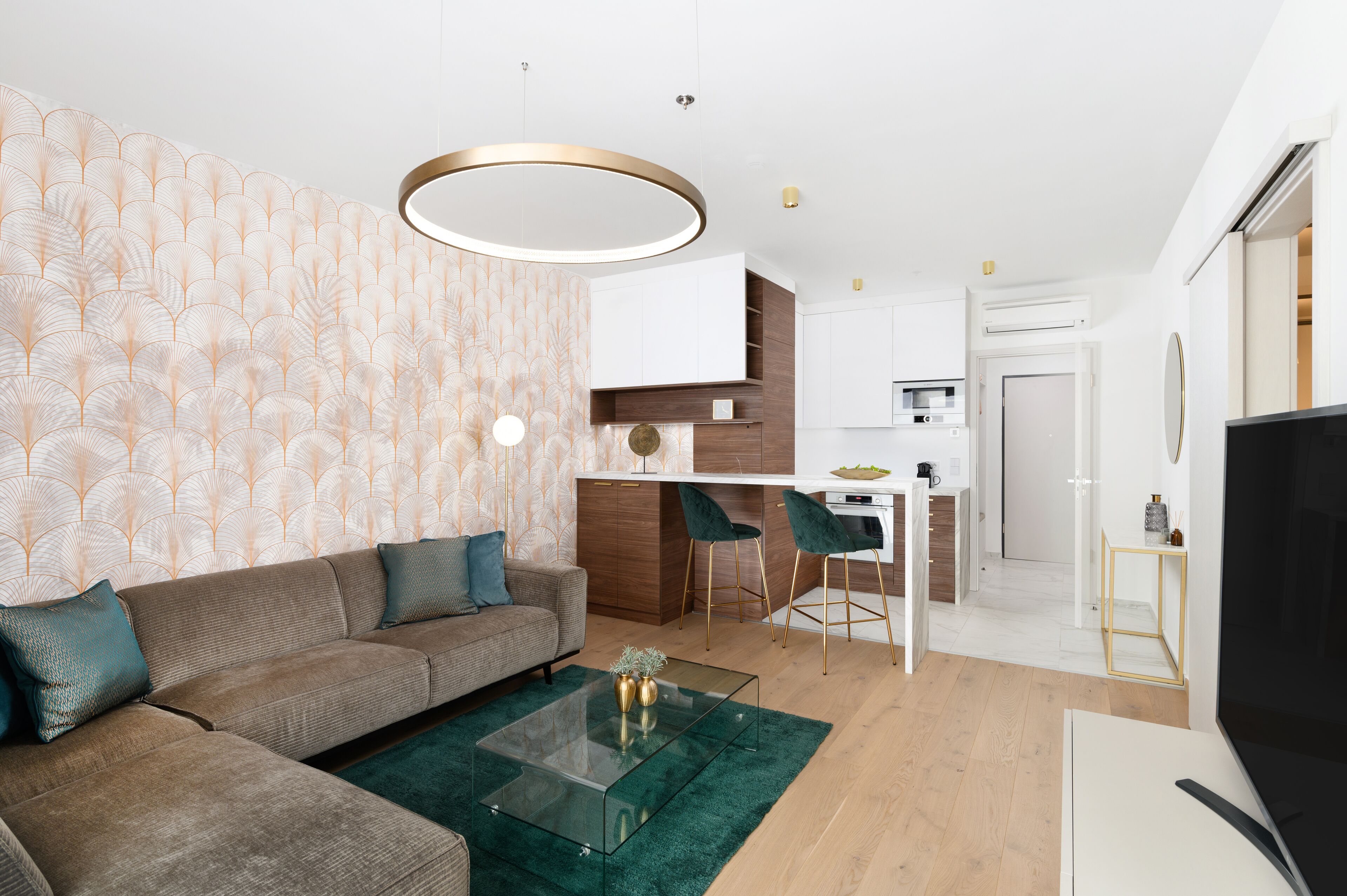 A modern living room with a sofa, coffee table, and a TV. There is a kitchen area with a dining table and chairs.