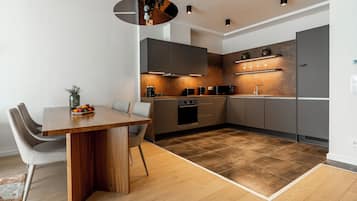 Eine moderne Küche mit Holztisch, grauen Schränken und einem eingebauten Backofen.