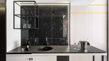 A modern kitchen with a black marble backsplash, a built-in sink, and a coffee machine.