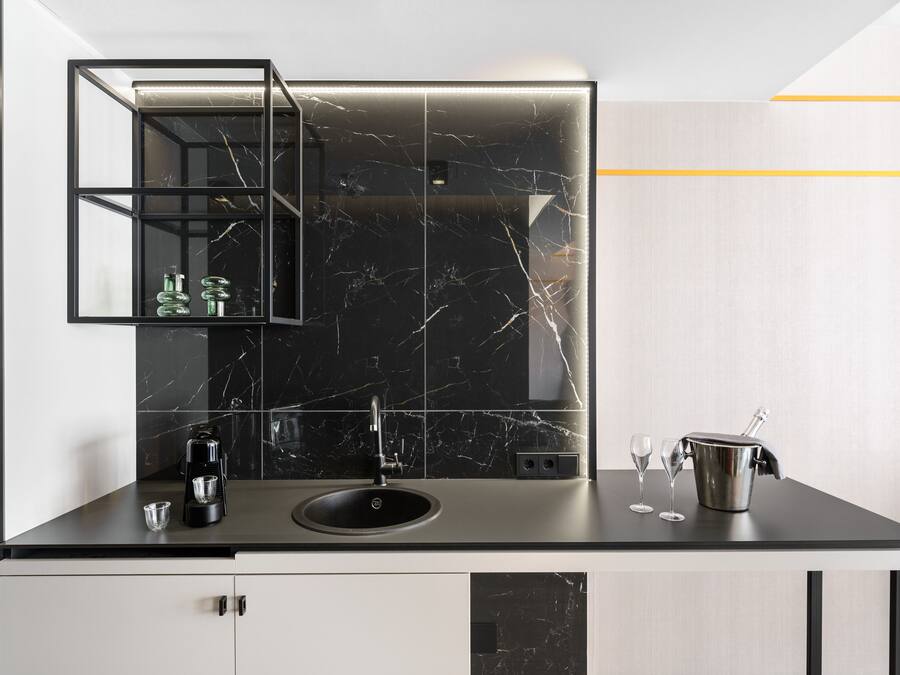 A modern kitchen with a black marble backsplash, a built-in sink, and a coffee machine.