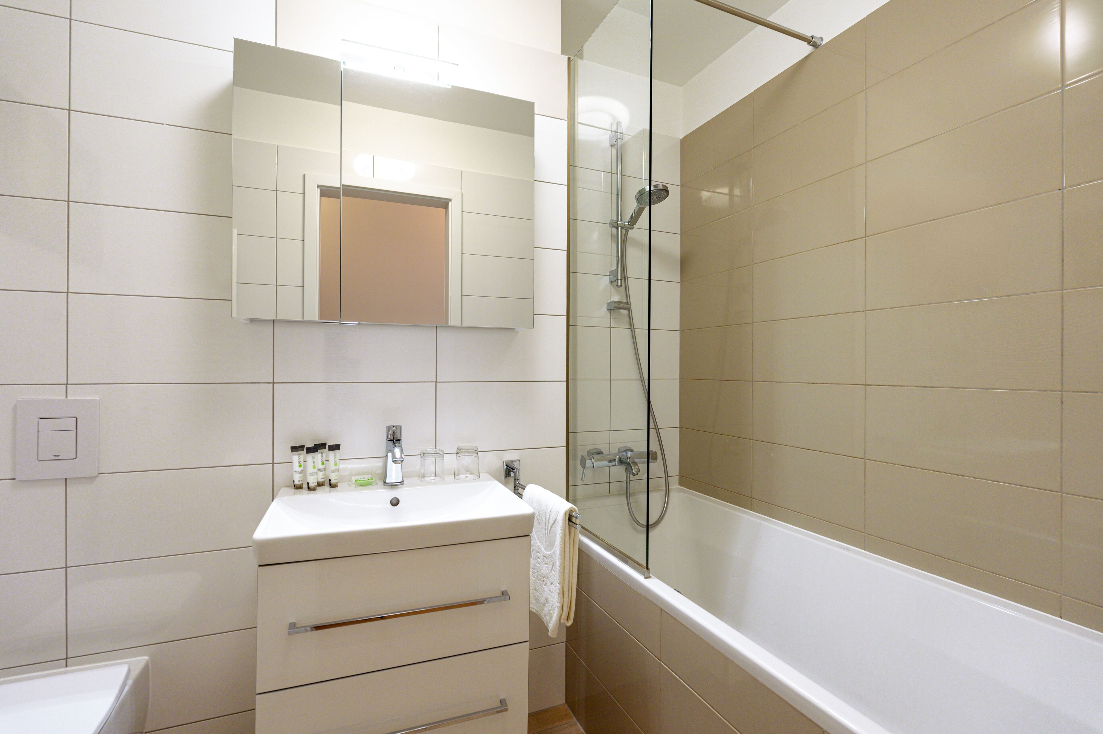 Un bagno con un lavandino bianco, uno specchio e una cabina doccia in vetro.