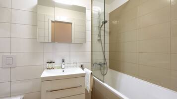 Un bagno con un lavandino bianco, uno specchio e una cabina doccia in vetro.
