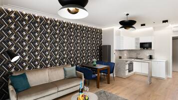 A modern living room with a sofa, dining table, and kitchen area.