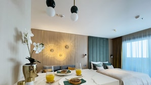 A modern hotel room with a dining area, a bed with a view, and decorative wall lights. - Emerald Downtown Suites (Budapest)