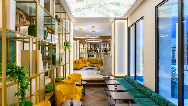 A modern interior with yellow seating, a green sofa, and a glass wall. - Emerald Downtown Suites (Budapest)