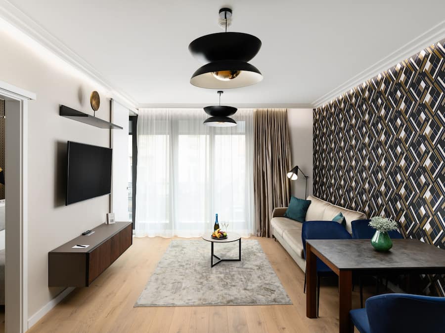 A modern living room with a flat-screen TV, a dining table, and a sofa.