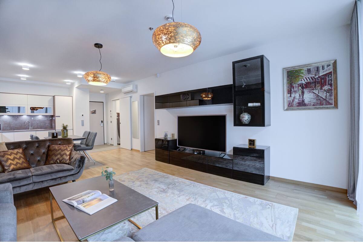 A modern living room with a sofa, coffee table, and a TV on a black entertainment unit.