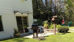 A well-maintained lawn with a barbecue grill and bird feeders in a residential setting.