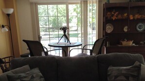A living room with a dark gray sofa, two armchairs, a small round table, and a tripod-mounted telescope.