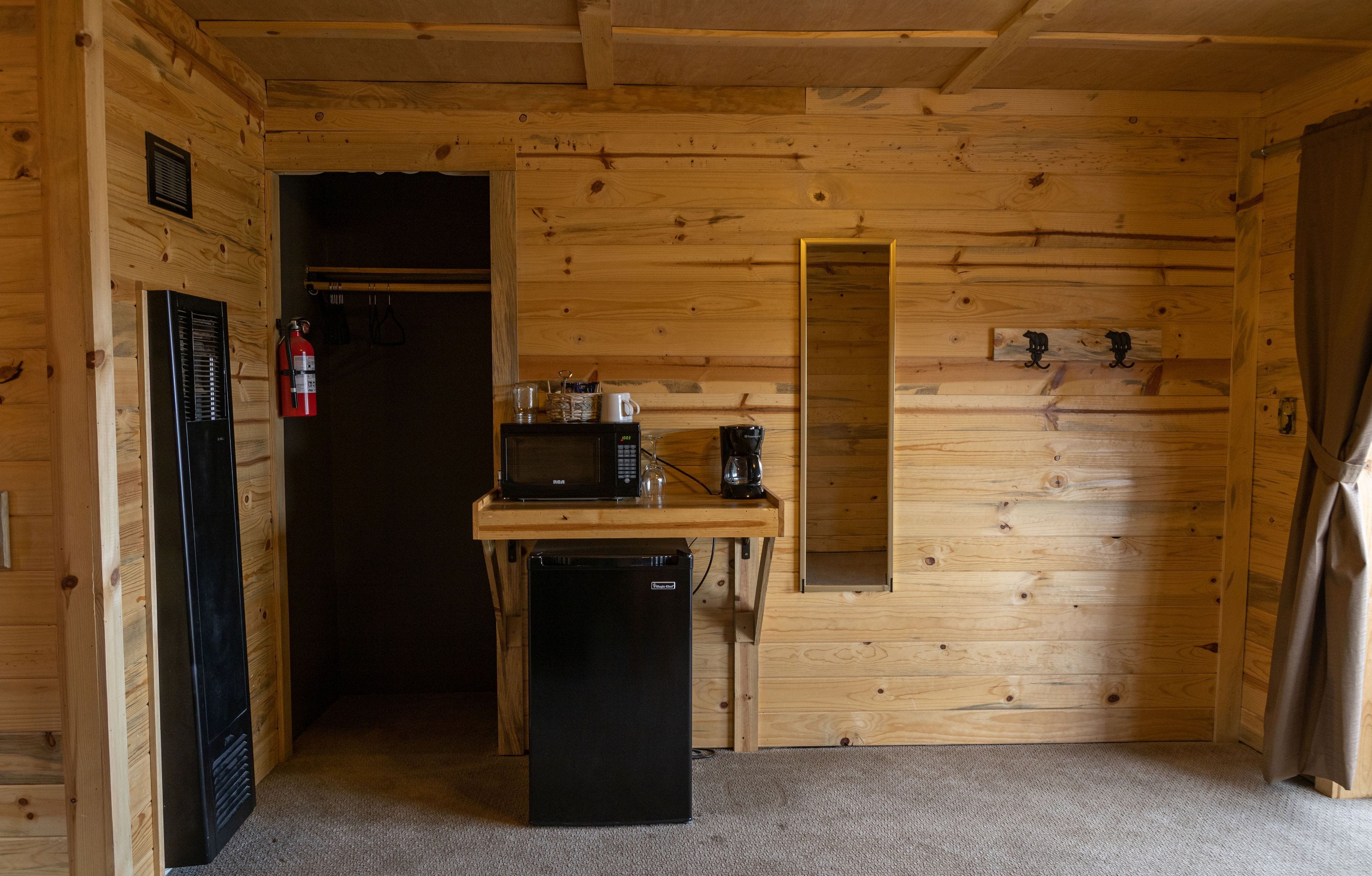 A compact kitchen with a refrigerator, microwave, and coffee maker on a wooden countertop.