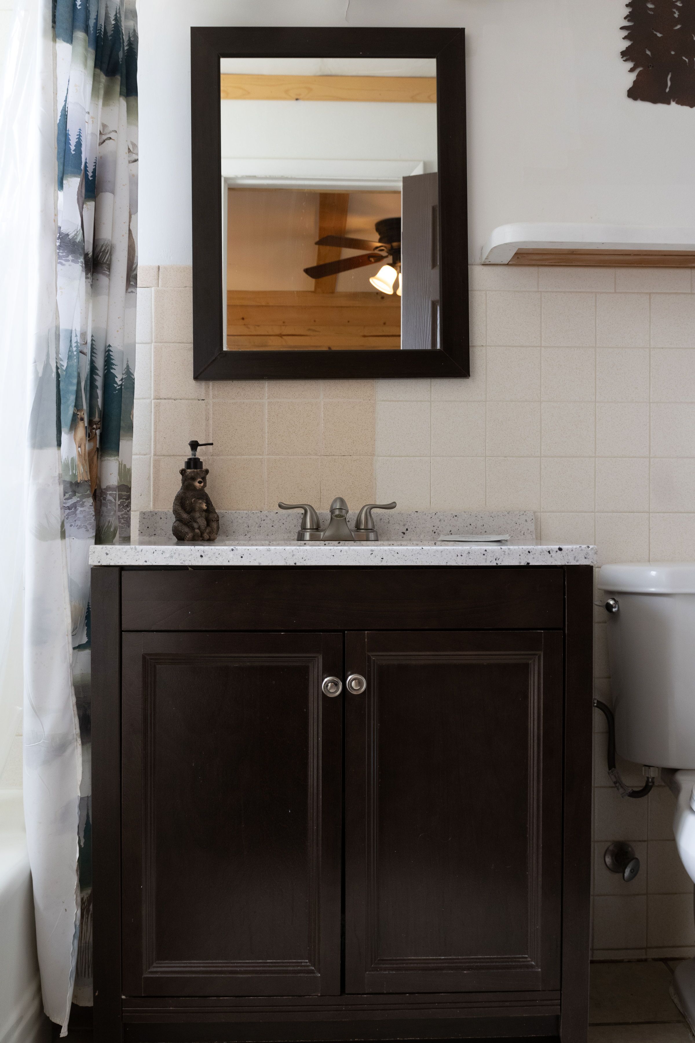 Une salle de bain avec un meuble-lavabo en bois foncé, un lavabo blanc et un miroir au-dessus.