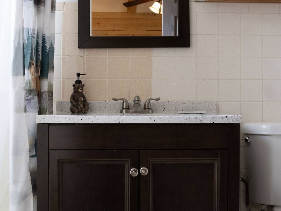 Une salle de bain avec un meuble-lavabo en bois foncé, un lavabo blanc et un miroir au-dessus.