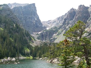 A mountainous landscape with a lake surrounded by dense forests and rocky cliffs. - Estes Lake Lodge (Estes Park)