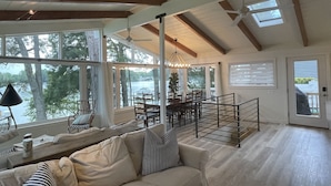 Un salon spacieux avec un plafond haut, de grandes fenêtres et une vue sur l’extérieur.