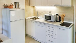 Una cucina compatta con frigorifero, lavastoviglie, microonde, lavello e bollitore.