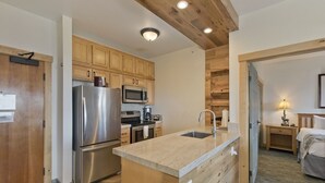 A modern kitchen with wooden cabinets, stainless steel appliances, and a central island with a sink. - Ski-in / Ski-out 2Bed 2Bath Sunstone Lodge Condo at Little Eagle Express (Mammoth Lakes)
