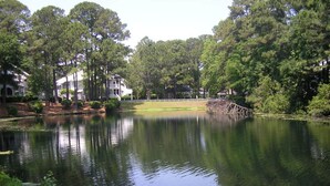 A serene lake with surrounding trees and a white building with a porch. - Fall / Snow Bird Special• 6-Min Walk to  Beach • Pool, Tennis -Gated–Hilton Head (Hilton Head)