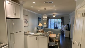 A compact kitchen with white cabinets, a granite countertop, a dining area with a table and chairs, and a ceiling fan. - Fall / Snow Bird Special• 6-Min Walk to  Beach • Pool, Tennis -Gated–Hilton Head (Hilton Head)