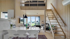 Amplio espacio tipo loft con comedor, escalera y vistas al exterior.