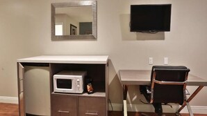 A compact room with a kitchenette, a flat-screen TV, and a foldable chair. - Hotel 414 Anaheim, Luxurious King Size Bed (Anaheim)